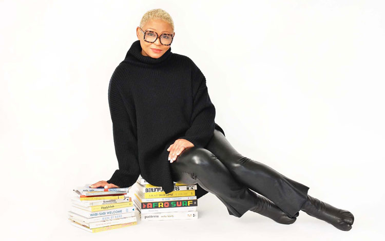 Woman wearing a black sweater in black leather pants and black leather shoes wearing glasses.